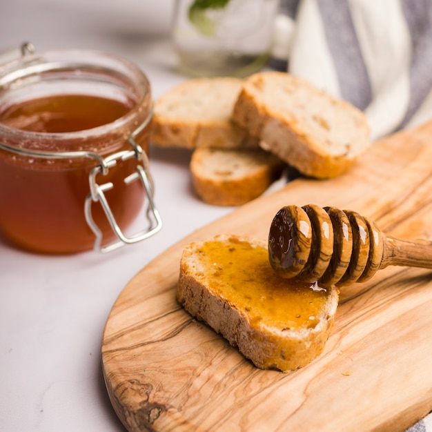 glass jar full of honey with honey spoon