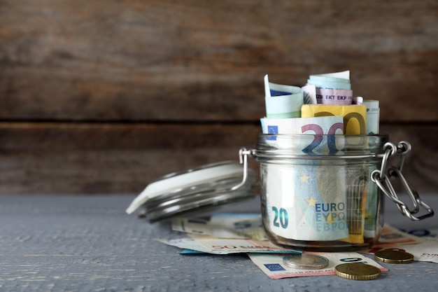 Glass jar full of money on wooden table Space for text