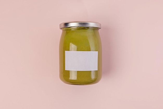 Photo glass jar of green pistachio paste isolated on pink background