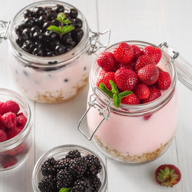 Glass jar of healthy yogurt with fresh berries, oats and mint on wooden table. healthy breakfast concept