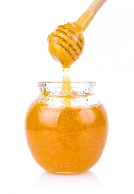 Glass jar of honey and stick isolated on white background