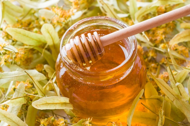 Photo glass jar of honey on the surface of linden blossoms