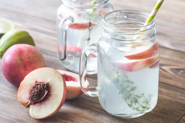 Glass jar of lime water with slices of peach