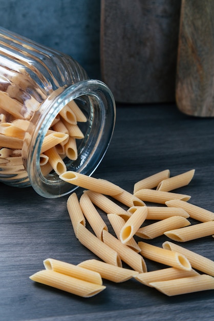 Glass jar lying down with pasta around it