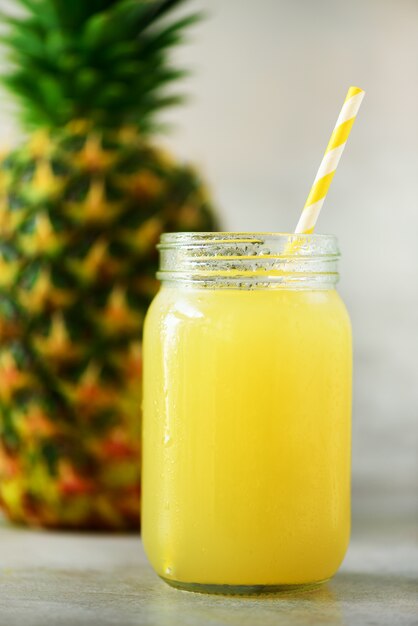 Glass jar of pineapple smoothie and whole fruit. Summer, holiday concept. Raw, vegan, vegetarian, clean eating diet.