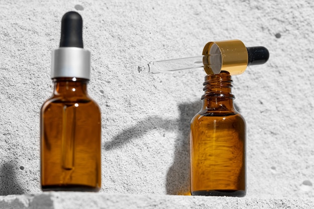 Glass jar of skincare serum on concrete block close up