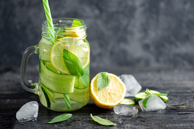 Vaso di vetro di limonata estiva con acqua fredda dietetica di menta e limone e cetriolo