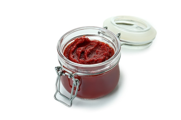 Glass jar of tomato paste isolated on white background