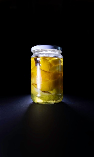 Glass jar with citrus peel and vodka on a black background liquor elaboration canning concept