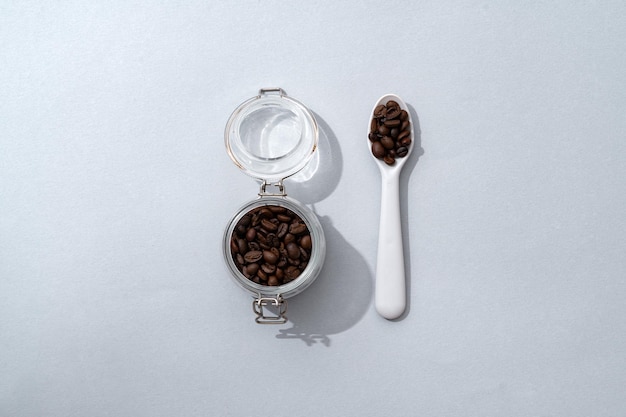 사진 회색 배경에 커피콩과 스푼이 있는 유리병