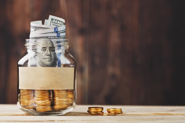 Photo glass jar with coins and dollars with a sticker with free space for text