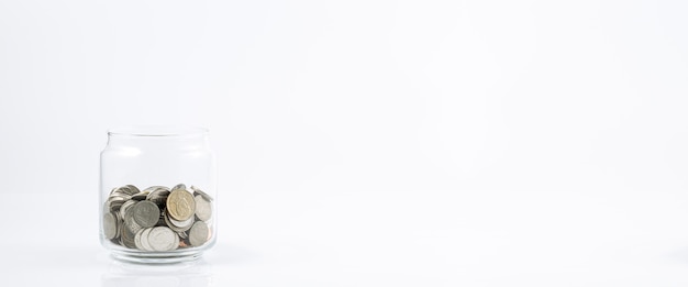 흰색 배경에 동전과 유리 항아리 흰색 배경에 고립 된 돈의 항아리