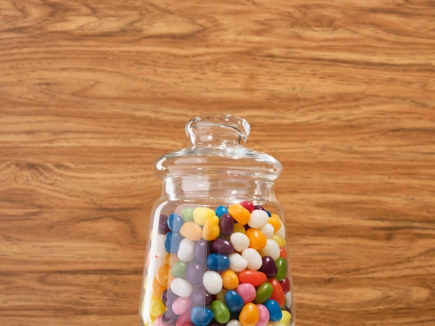 Glass jar with colored candies on a wooden background Different childs sweets