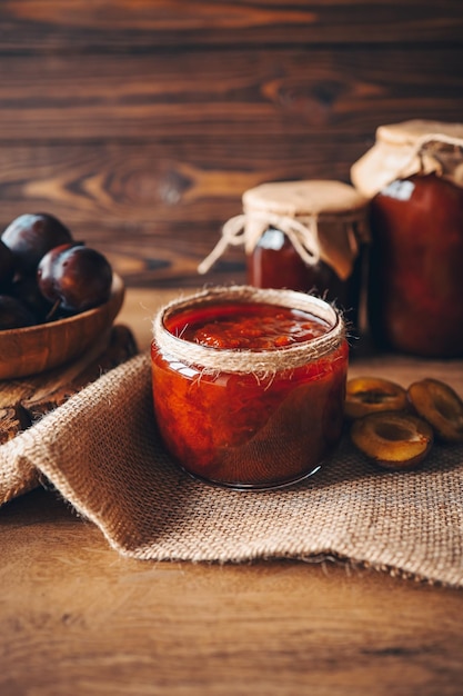 Glass jar with delicious homemade plum jam on table