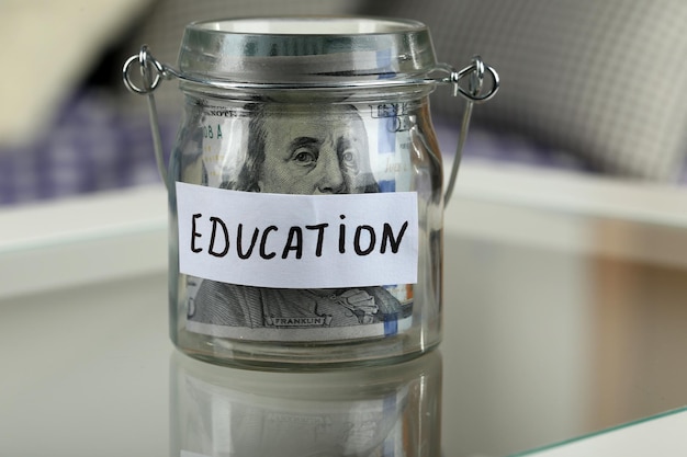 Glass jar with dollar banknotes for education on a table
