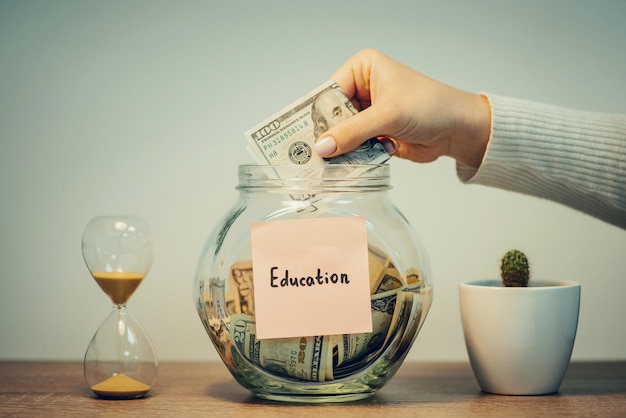 Glass jar with dollar bills and inscription Education Saving money for higher education concept toned photo