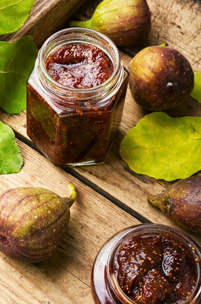 Glass jar with fig jam on rustic wooden table