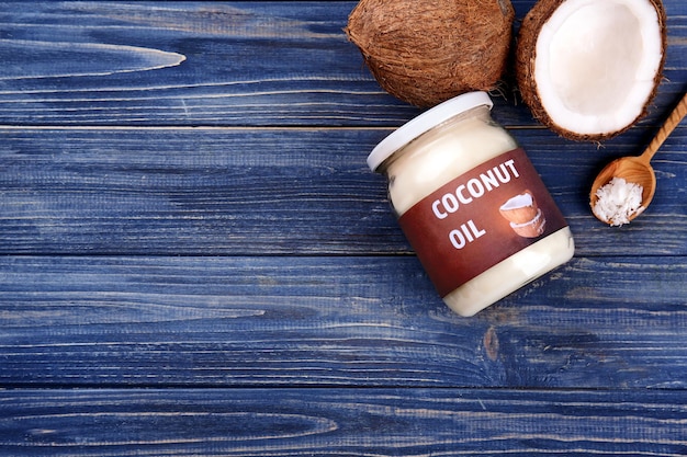 Glass jar with fresh coconut oil on wooden background