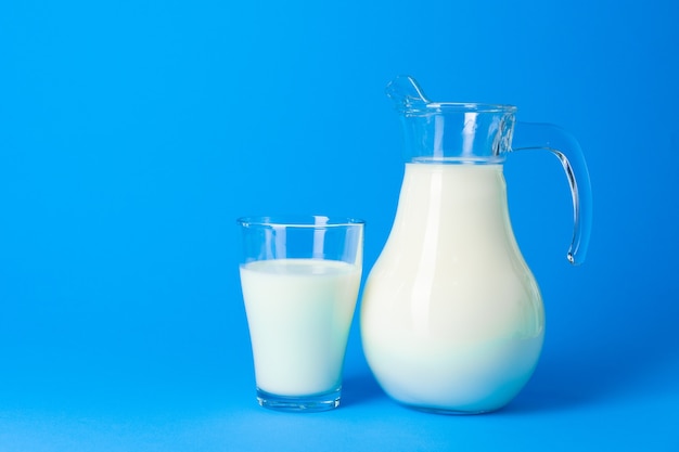 Glass jar with fresh milk against blue background close up