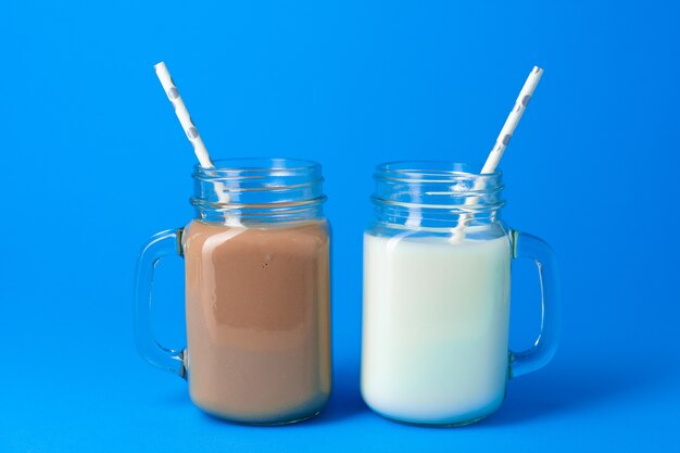 Glass jar with fresh milk against blue