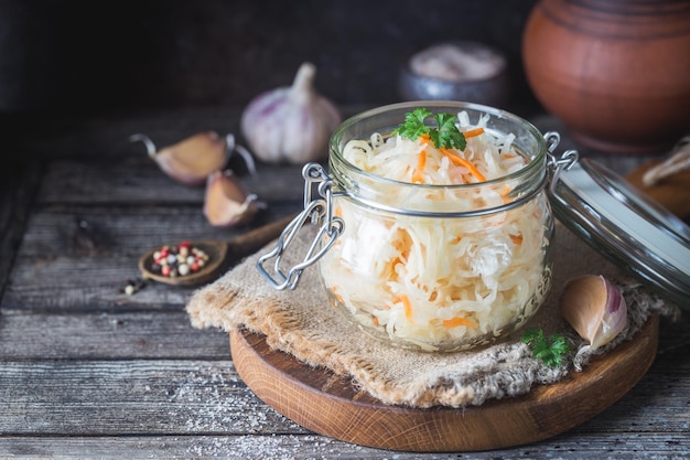 Glass jar with homemade sauerkraut on rustic wooden table