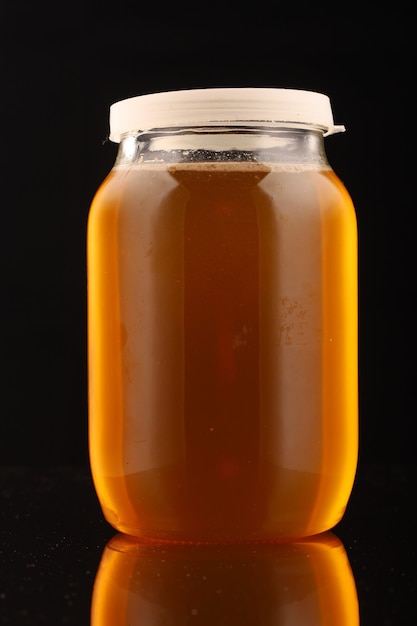 Glass jar with honey isolated on black