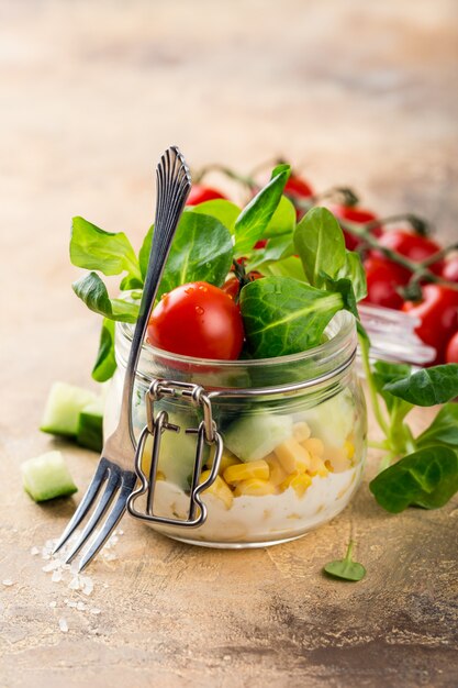 Glass jar with lamb's lettuce and vegetables salad. 