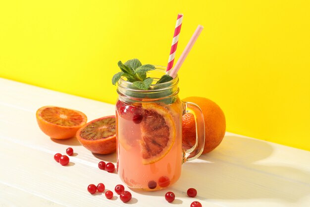 Glass jar with lemonade and ingredients on wooden table. Fresh drink