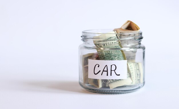 Glass jar with money closeup on a white background Piggy bank with dollars for the car Save money