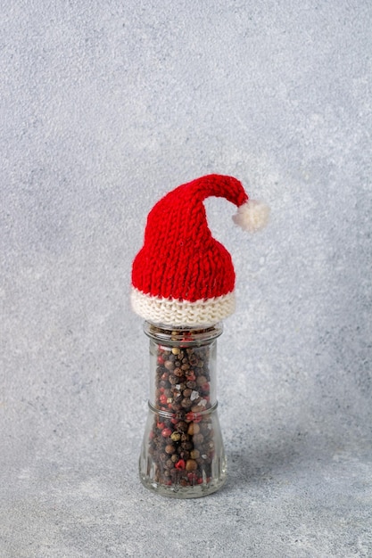 Glass jar with pepper seeds in Santa Claus hat vertical orientation