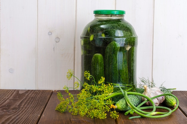 Glass jar with pickled cucumbers and herbs