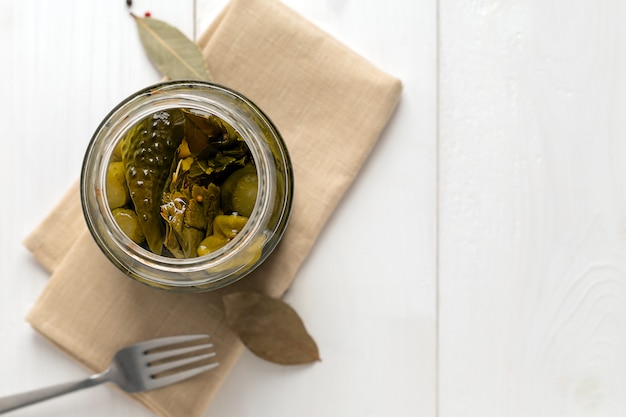 Glass jar with pickled cucumbers on white background