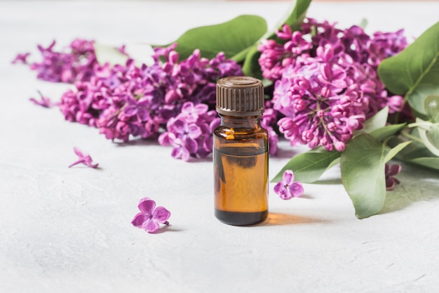 Glass jar with rose water and lilac flowers