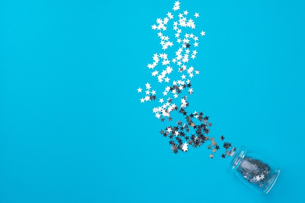 Glass jar with scattered confetti on blue top view