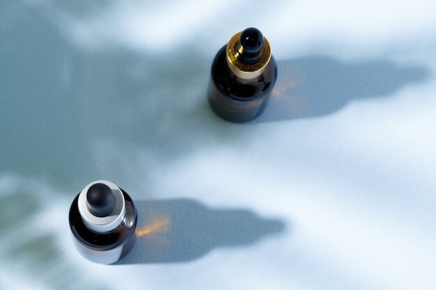 Glass jar with skincare liquid on gray background with shadow