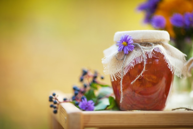 Glass jar with tasty apricot jam on a table. Autumn time