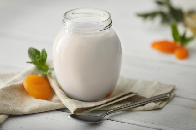 Glass jar with tasty yogurt on wooden background