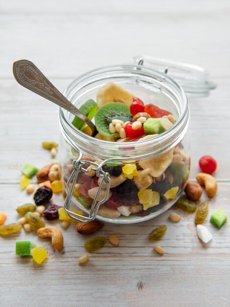 Glass jar with various dried fruits and nuts on a wooden  surface