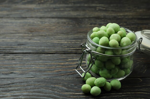 Glass jar with wasabi nuts on rustic wooden background