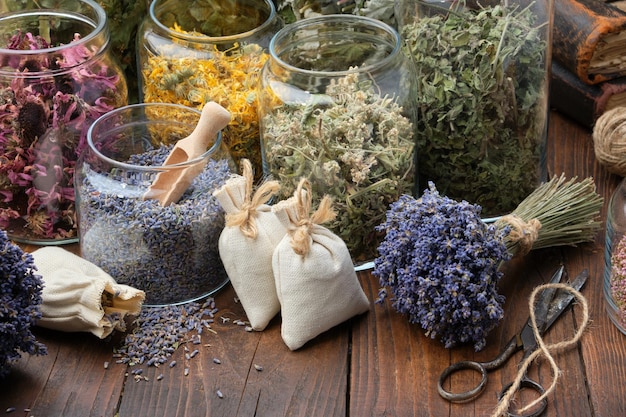 Glass jars of dry medicinal herbs aromatic sachets bunches of dry lavender Alternative medicine