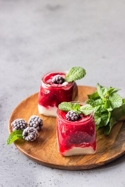 민트와 함께 건강 한 계층화 된 혼합 딸기와 요구르트 스무디의 유리 용기