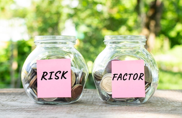 Glass jars with coins and the inscriptions risk and factor stand on a wooden table investment budget