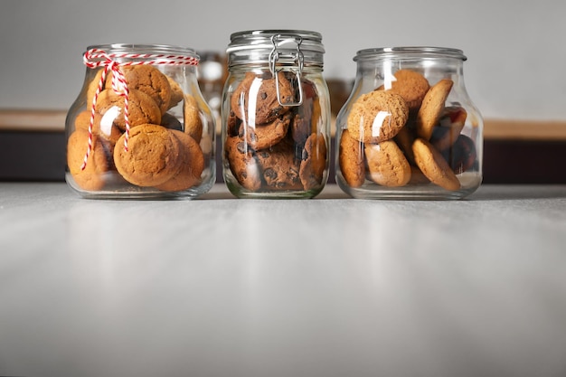 Glass jars with delicious oatmeal cookies on wooden table