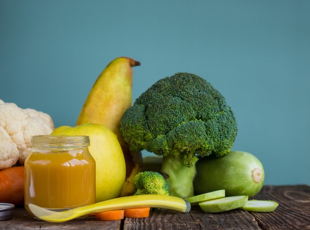 Glass jars with natural vegetable baby food puree on wooden table