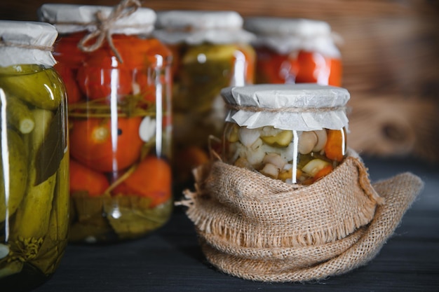 Glass jars with pickled cucumbers pickles pickled tomatoes and cabbage Jars of various pickled vegetables Canned food in a rustic composition