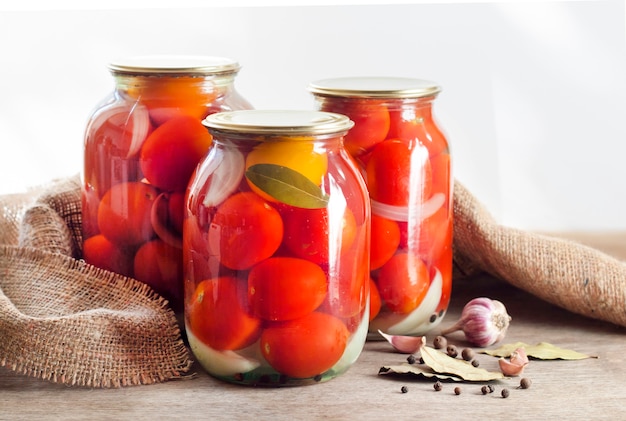 Glass jars with red pickled tomatoes, sealed with metal lid