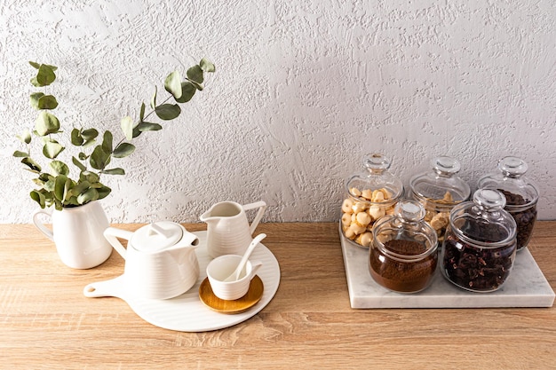 Photo glass jars with tea coffee sugar on a marble board and tea items on the kitchen countertop part of a fragment of a modern kitchen