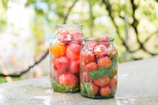 Glass jars with vegetables tomatoes in nature on a rustic kitchen table healthy homemade food