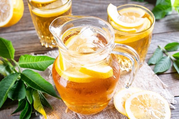 Glass jug of cold lemonade on wooden table