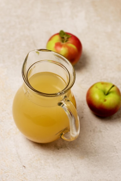 Glass Jug With Apple Juice with Pulp Raw Red Apples on Concreet Background Vertical